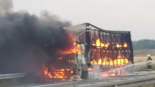 Strażacy gaszą płonącą ciężarówkę na autostradzie A4, ogień objął także pobliskie pole zbożowe.