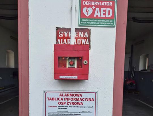 Defibrylator AED zamontowany na budynku remizy OSP Żyrowa z tablicą informacyjną