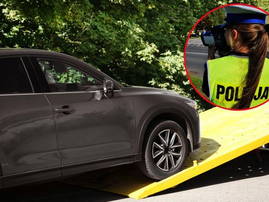 na zdjęciu holowany samochód konfiskata auta promile i policjantka celuje radarem.jpg