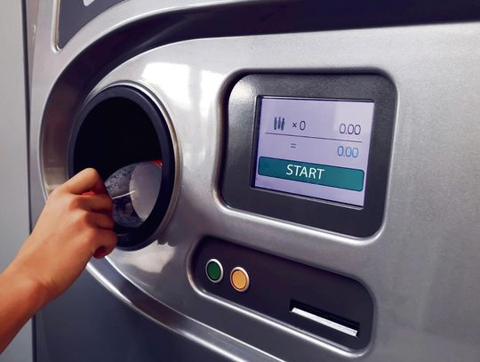 „Automat do zwrotu butelek i puszek w jednym z polskich sklepów — widoczne opakowania w systemie kaucyjnym.”