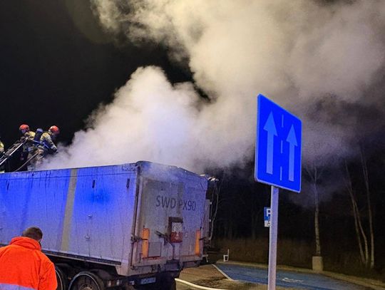 Strażacy gaszą pożar naczepy samochodu ciężarowego z koksem na wjeździe na autostradę A4 w powiecie krapkowickim nocą.