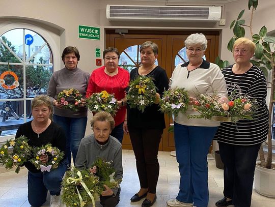 Seniorzy z gminy Strzeleczki podczas warsztatów Aktywni 60+ tworzą wielkanocne wianki z kwiatów i dekoracji.