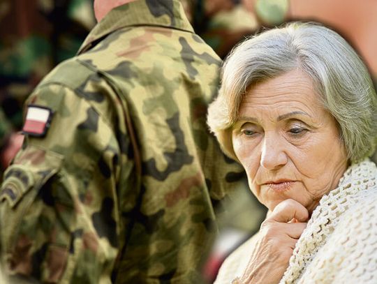 Starsza kobieta siedząca samotnie w domu, symbol problemu opiekunów osób chorych podczas obowiązkowych ćwiczeń wojskowych członków rodziny