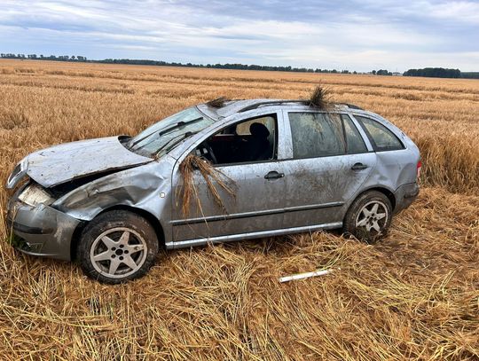 Rozbita skoda po dachowaniu w Straduni, stojąca w polu przy drodze krajowej nr 45, w tle strażacy i służby ratunkowe