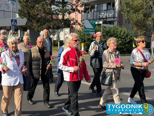 Seniorzy podczas gminnych obchodów Dnia Seniora w Zdzieszowicach – kolorowy orszak z orkiestrą maszeruje ulicami miasta.