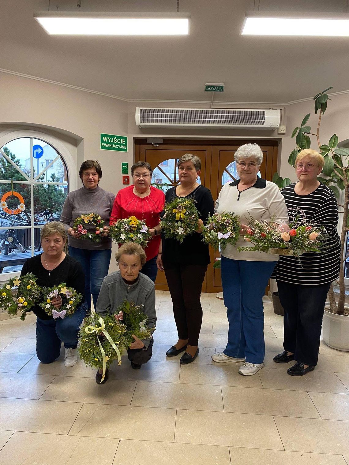 Seniorzy z gminy Strzeleczki podczas warsztatów Aktywni 60+ tworzą wielkanocne wianki z kwiatów i dekoracji.