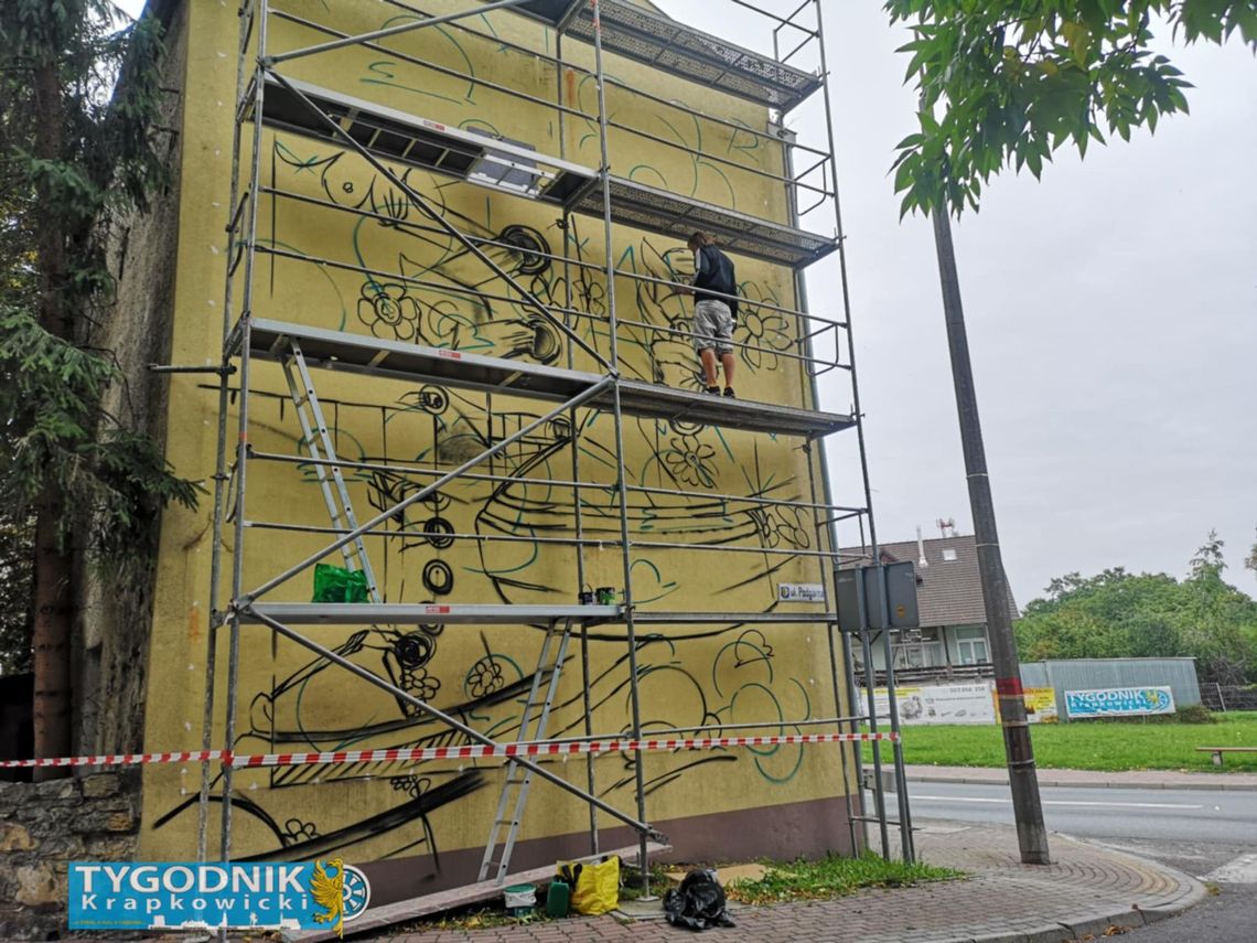 Na zdjęciu artysta pracujący na rusztowaniu przy ścianie kamienicy w Krapkowicach, gdzie powstaje nowy mural z motywem trampków.