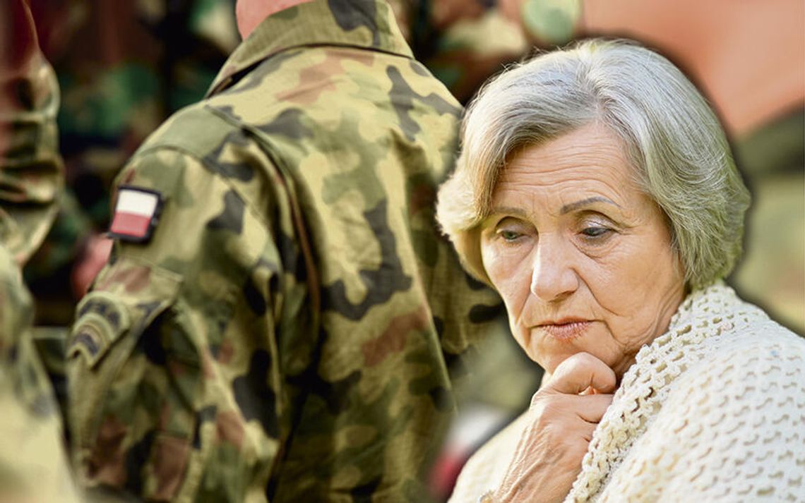 Starsza kobieta siedząca samotnie w domu, symbol problemu opiekunów osób chorych podczas obowiązkowych ćwiczeń wojskowych członków rodziny