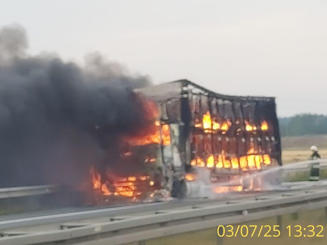Strażacy gaszą płonącą ciężarówkę na autostradzie A4, ogień objął także pobliskie pole zbożowe.